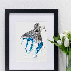 May include: A black and white drawing of a fish with blue paint dripping from its tail. The drawing is framed in a black frame and is displayed on a white wall.