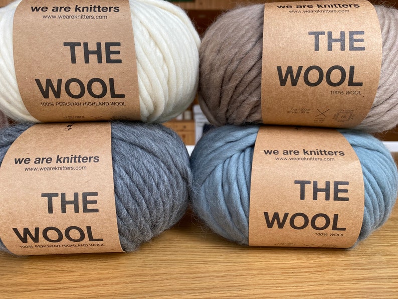 May include: Four balls of yarn in different colors, including white, beige, gray, and blue. Each ball has a label that reads "We Are Knitters" and "The Wool" with the percentage of wool content.