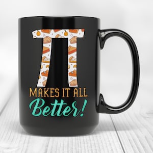 May include: Black ceramic mug with a large Pi symbol filled with pie slices and the text "MAKES IT ALL BETTER!" in orange and teal. The mug has a large handle and is set against a blurred background.