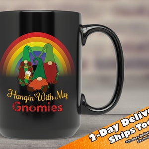 May include: Black ceramic coffee mug featuring a rainbow and three gnomes holding beer mugs. The text "Hangin' With My Gnomies" is printed on the mug.