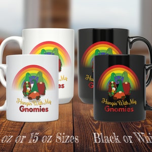 May include: Two ceramic coffee mugs featuring a rainbow and gnome design. The text on the mugs reads "Hangin' With My Gnomies". The mugs are available in 11 oz or 15 oz sizes and in black or white.