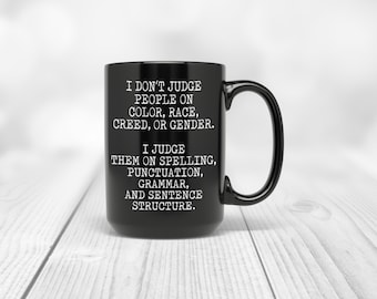 Puede incluir: Taza de café negra con texto blanco que dice: "No juzgo a las personas por su color, raza, credo o género. Las juzgo por su ortografía, puntuación, gramática y estructura de las oraciones."