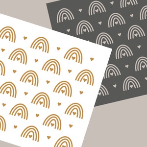 Könnte beinhalten: Zwei Papierbögen mit sich wiederholenden Mustern aus Regenbogen und Herzen. Ein Bogen ist weiß mit goldenen Regenbogen und Herzen, der andere ist dunkelgrau mit weißen Regenbogen und Herzen. Der Text "Joyous Times" steht unten.