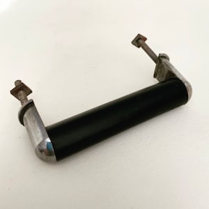 May include: A black and silver cabinet pull with a rounded rectangular shape. The pull has a black plastic handle and silver metal ends.