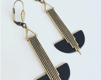 May include: A pair of gold earrings with black semi-circle accents. The earrings have a geometric design with vertical lines.
