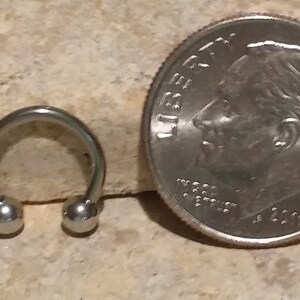 May include: A silver horseshoe-shaped body piercing with two round balls on the ends.