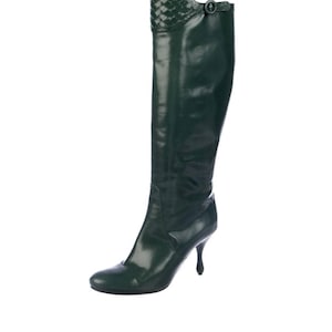 May include: Green leather knee-high boots with a woven detail at the top and a small heel.