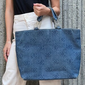 May include: A blue denim tote bag with a clear plastic handle and a repeating pattern of the letter "C".