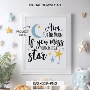 May include: A white framed print with a blue crescent moon and yellow stars. The text reads "Aim for the moon. If you miss you may hit a star."