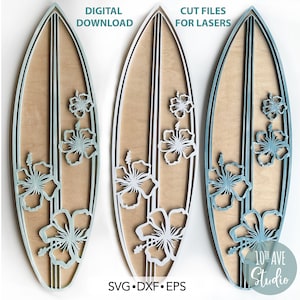 May include: Three digital cut files for a surfboard with hibiscus flowers. The files are available in SVG, DXF, and EPS formats. The surfboard is a light brown color with white and blue accents. The hibiscus flowers are white and blue. The text "DIGITAL DOWNLOAD" is at the top of the left image. The text "CUT FILES FOR LASERS" is at the top of the right image. The text "SVG.DXF.EPS" is at the bottom of the center image. The text "10th AVE Studio" is at the bottom of the right image.