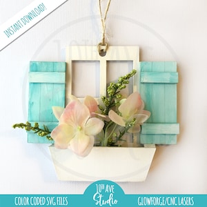 May include: White wooden window with blue shutters and a flower box filled with pink flowers. The window is hanging from a string and has the text "10th Ave Studio" printed below it.