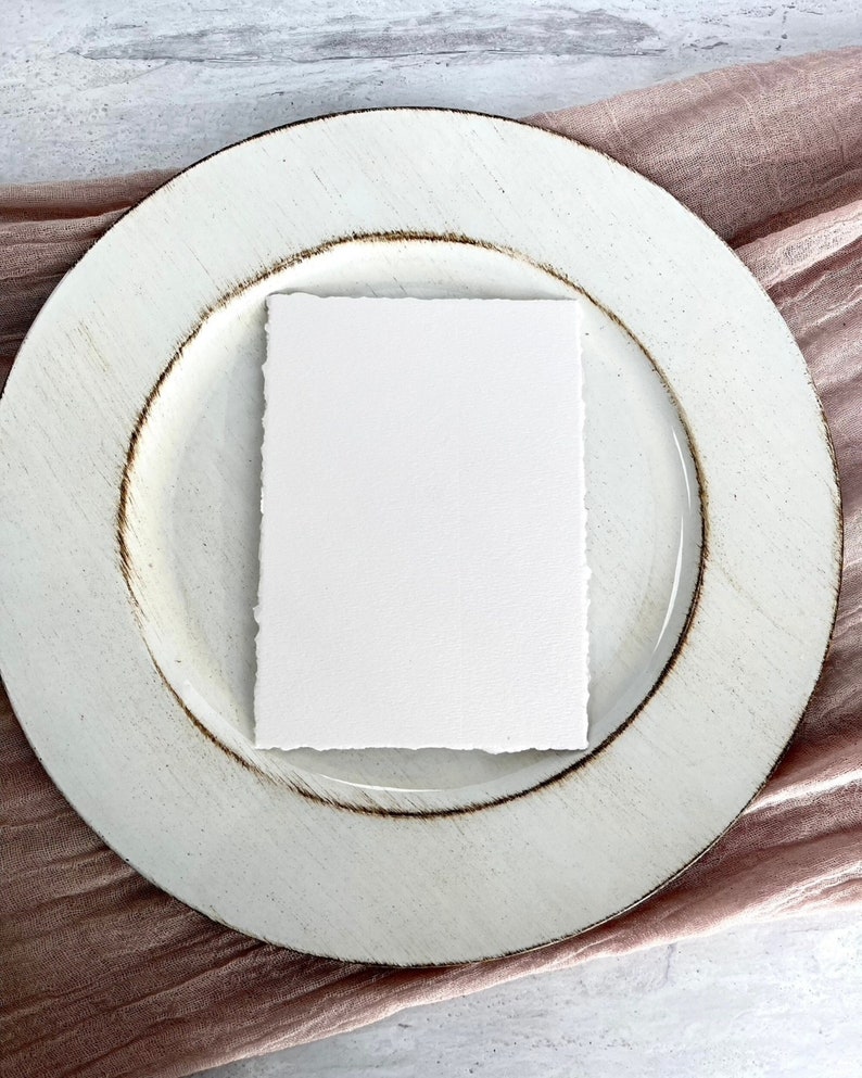 A sheet of our 5x7 inch handmade soft white deckle edge paper on a plate to show it could be used as a menu for a wedding or event