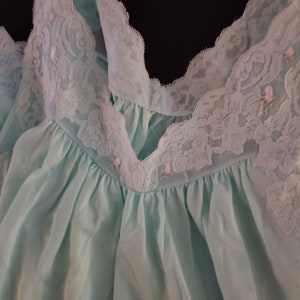 May include: A light blue, sheer nightgown with a delicate lace trim around the neckline. The lace is white with a pink floral pattern.