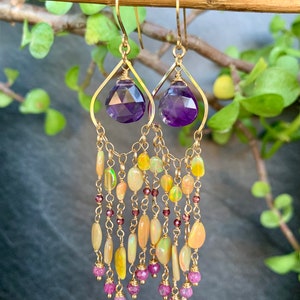 May include: Gold dangle earrings with a purple amethyst gemstone at the top and a cascade of opal and ruby beads.