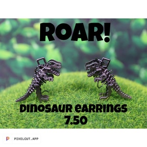 May include: A pair of silver dinosaur skeleton earrings. The earrings are on a green background with the text "ROAR! Dinosaur earrings 7.50".