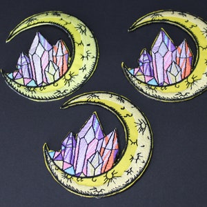 May include: Three yellow crescent moon embroidered patches with a cluster of purple, pink, and orange crystals in the center of each moon.
