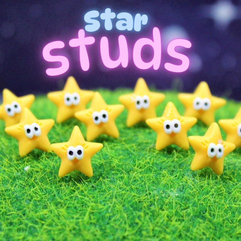 Group of small yellow star-shaped stud earrings with googly eyes, arranged on bright green grass-effect display with a night sky background and the words ‘star studs’ in playful pastel letters.  Perfect for gifting or keeping, these star stud earrings slip effortlessly from brunch to date night and layer beautifully with other minimalist studs.