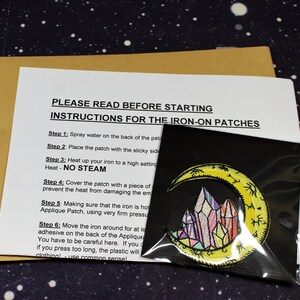 May include: Instructions for applying iron-on patches. The instructions include steps for preparing the fabric, applying heat, and removing the protective backing. The image also shows a yellow crescent moon with colorful crystals inside, which is an example of an iron-on patch.