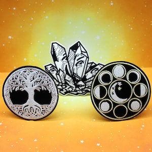 May include: Three embroidered patches: a black and white crystal design, a black circle with a white tree of life, and a black circle with white moon phases and stars. The patches are on a yellow background with white stars.