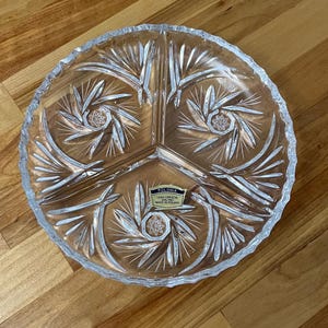 Könnte beinhalten: Eine klare Glasservierplatte mit vier Abschnitten, die mit einem geschliffenen Kristallmuster verziert ist. Die Platte trägt ein Etikett mit der Aufschrift "Polonia Lead Crystal Made in Poland".