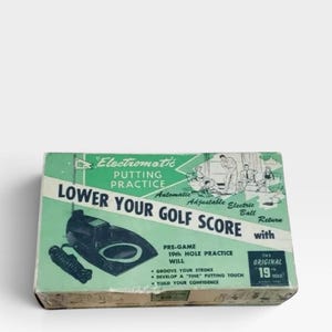 以下が含まれることがあります： ライトグリーンと白のヴィンテージElectromatic Putting Practiceの箱。箱にはゴルフをする人々のイラスト、「Lower Your Golf Score with Automatic Adjustable Electric Ball Return」、「The Original 19th Hole」というテキストが記載されています。