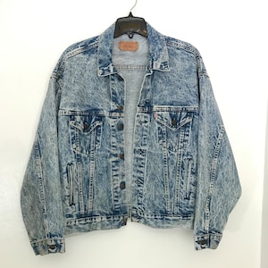 May include: A light blue acid wash denim jacket with a button closure and two front pockets.