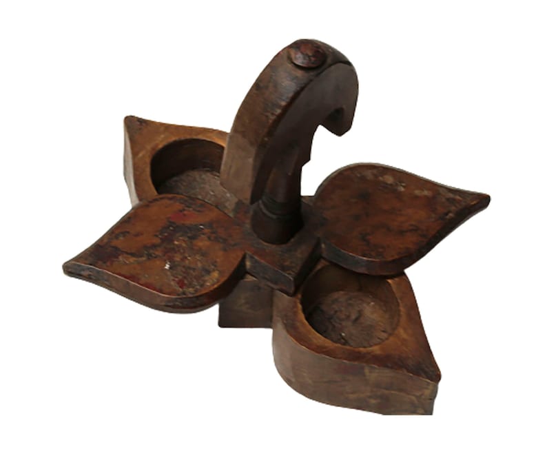 May include: A wooden spice rack shaped like a flower with three compartments. The rack has a handle on top and is made of dark brown wood.