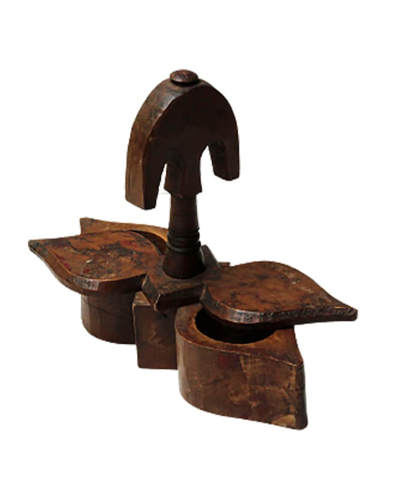 May include: A wooden spice box with three compartments, each shaped like a leaf. The box has a decorative top with a knob. The box is made of dark brown wood and has a rustic appearance.