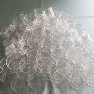 May include: A large pile of clear plastic votive candle holders. The holders are stacked on top of each other and are all the same size. The text "Bees Light Candles" is visible in the centre of the image.