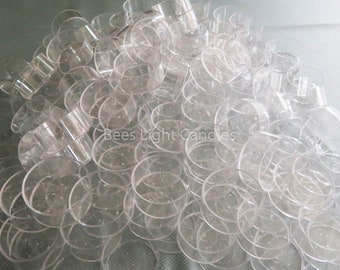 May include: A large pile of clear plastic votive candle holders. The holders are stacked on top of each other and are all the same size. The text "Bees Light Candles" is visible in the centre of the image.