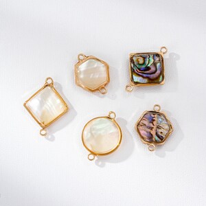May include: Five gold-toned jewelry pendants in various shapes: a diamond, a hexagon, a square, a circle, and another hexagon. Each pendant features a mother-of-pearl or iridescent abalone shell inlay. The pendants have small loops for attaching to a chain or other jewelry components.