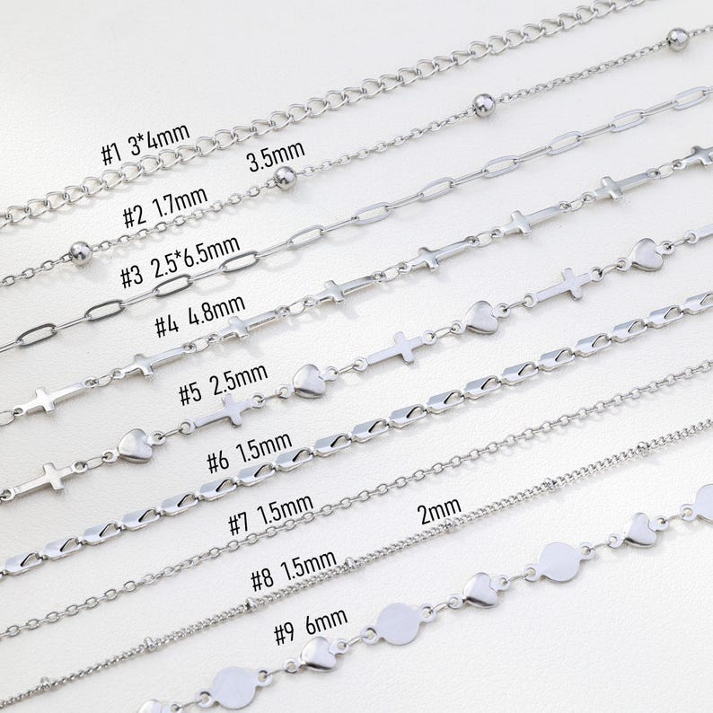May include: A collection of nine silver-colored chain necklaces, each with a unique design. The chains vary in style, including ball, oval link, cross, heart, and disc shapes. Measurements are provided for each chain, ranging from 1.5mm to 6mm in width.