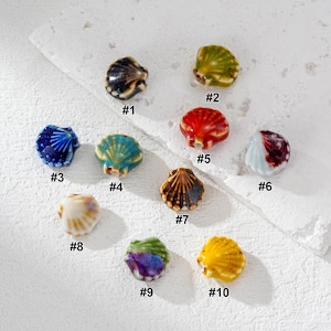 以下が含まれることがあります： 青、緑、赤、黄色など、さまざまな色の陶器製の貝殻ビーズ10個のコレクション。 各ビーズは、ジュエリー作りやクラフトプロジェクトに最適な、詳細なテクスチャとパターンで独自に設計されています。