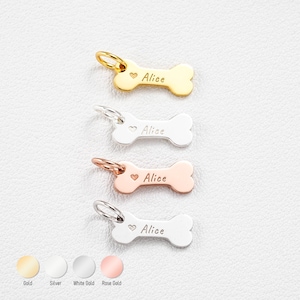 May include: Four bone-shaped pet tags in gold, silver, white gold, and rose gold. Each tag has a heart symbol and the name "Alice" engraved. The tags have a small loop for attaching to a collar.
