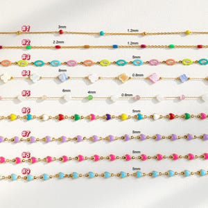 May include: Nine gold chains with different colored enamel beads. The chains are numbered 1 through 9. The beads are in various shapes, including hearts, circles, and flowers. The chains are all approximately 18 inches long.