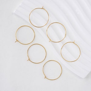 May include: Five gold hoop earrings of varying sizes. The hoops are all simple and circular, with no embellishments.