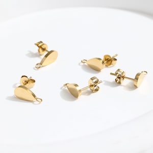Puede incluir: Cuatro hallazgos de pendientes de color dorado con forma de lágrima. Cada hallazgo tiene un bucle en un extremo y un poste en el otro.