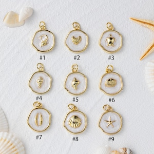 May include: Nine gold-coloured pendants featuring sea-themed designs like a dolphin, turtle, and starfish, set against white enamel. Each pendant has a gold loop for attachment. The pendants are numbered #1 to #9.