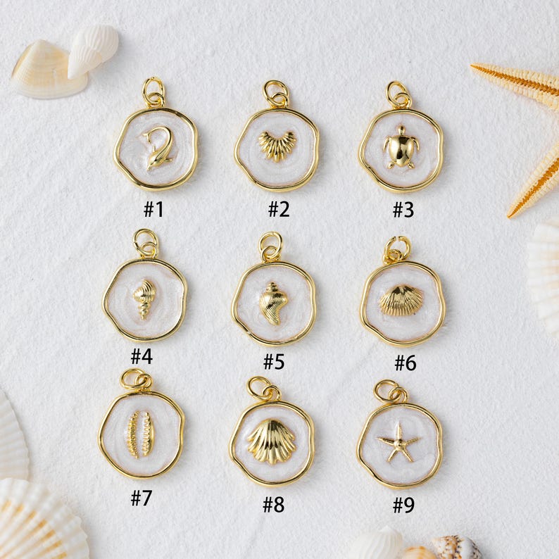 May include: Nine gold-coloured pendants featuring sea-themed designs like a dolphin, turtle, and starfish, set against white enamel. Each pendant has a gold loop for attachment. The pendants are numbered #1 to #9.