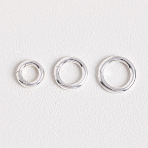 May include: Three silver jump rings of different sizes. The rings are open and have a smooth finish.