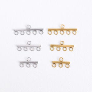 May include: Four silver and four gold slider clasps for jewelry making. Each clasp has a bar with five loops.