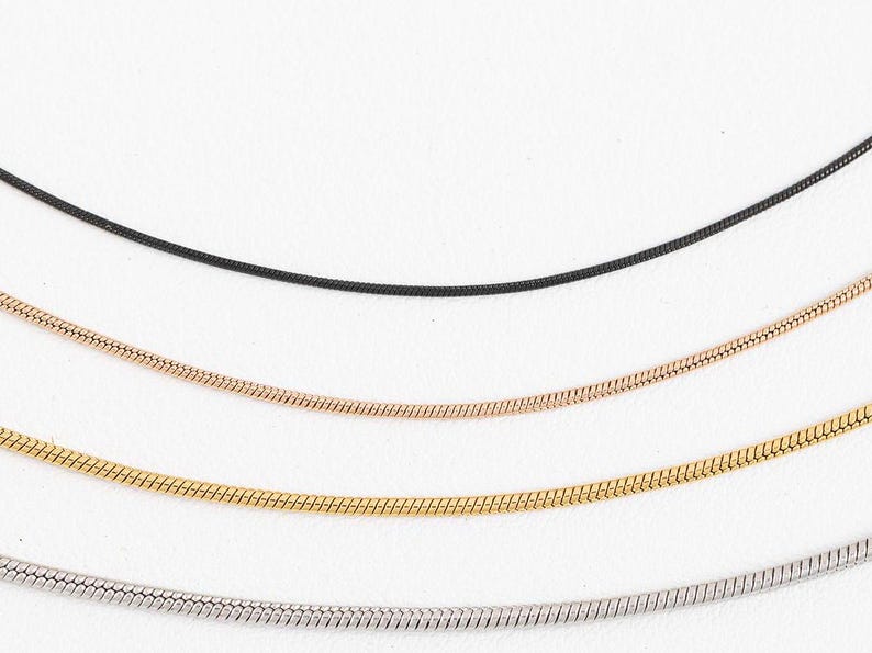 May include: Four different types of chain necklaces, including black, rose gold, gold, and silver.