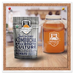 K&ouml;nnte beinhalten: Ein wei&szlig;er Beutel mit einem blauen und orangefarbenen Etikett, auf dem "Jun SCOBY Kombucha Live Starter Culture Makes One Gallon Always - Organic - Fresh -" steht. Der Beutel liegt auf einer Holzoberfl&auml;che neben einem durchsichtigen Glasgef&auml;&szlig; mit einem wei&szlig;en Stoffdeckel, gef&uuml;llt mit einer hellorangen Fl&uuml;ssigkeit. Das Gef&auml;&szlig; tr&auml;gt ein wei&szlig;es Etikett mit dem Text "FERMENTAHOLICS.COM".