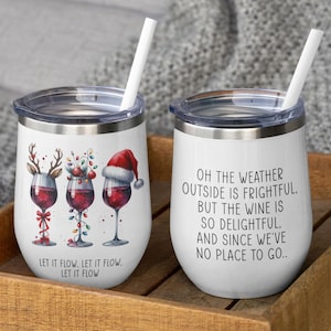 Peut inclure: Deux gobelets à vin en acier inoxydable avec couvercles et pailles. Un gobelet présente un motif sur le thème de Noël avec trois verres à vin décorés d'un renne, de lumières et d'un chapeau de Père Noël. L'autre gobelet a un fond blanc avec le texte "Oh the weather outside is frightful, but the wine is so delightful. And since we've no place to go."