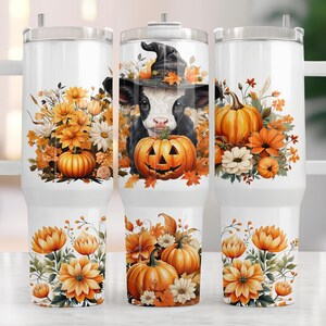 Könnte beinhalten: Ein weißer Isolierbecher mit Henkel, bedruckt mit einer schwarz-weißen Kuh mit Hexenhut, umgeben von orangefarbenen Kürbissen, Herbstblättern sowie gelben und weißen Herbstblumen auf einem weißen Untergrund.