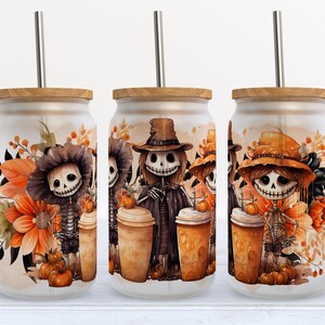 May include: Three frosted glass can-shaped tumblers with bamboo lids and metal straws. Each features a printed illustration of skeletons wearing hats, surrounded by orange flowers and pumpkins in a fall-themed color palette.