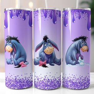 May include: Three purple stainless steel tumblers with a purple glitter bottom. Each tumbler features a cartoon image of Eeyore from Winnie the Pooh. The tumblers have a purple drip design.