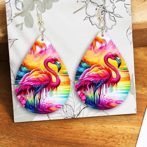 May include: A pair of teardrop-shaped earrings with a colorful flamingo design. The earrings are made of a white material and have a silver hook.