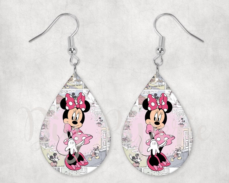 Op de afbeelding: Druppelvormige oorbellen met Minnie Mouse. Minnie draagt een roze jurk met stippen en een strik, tegen een stripachtergrond. Zilverkleurige oorhaakjes. Een speels accessoire voor Disney-fans.