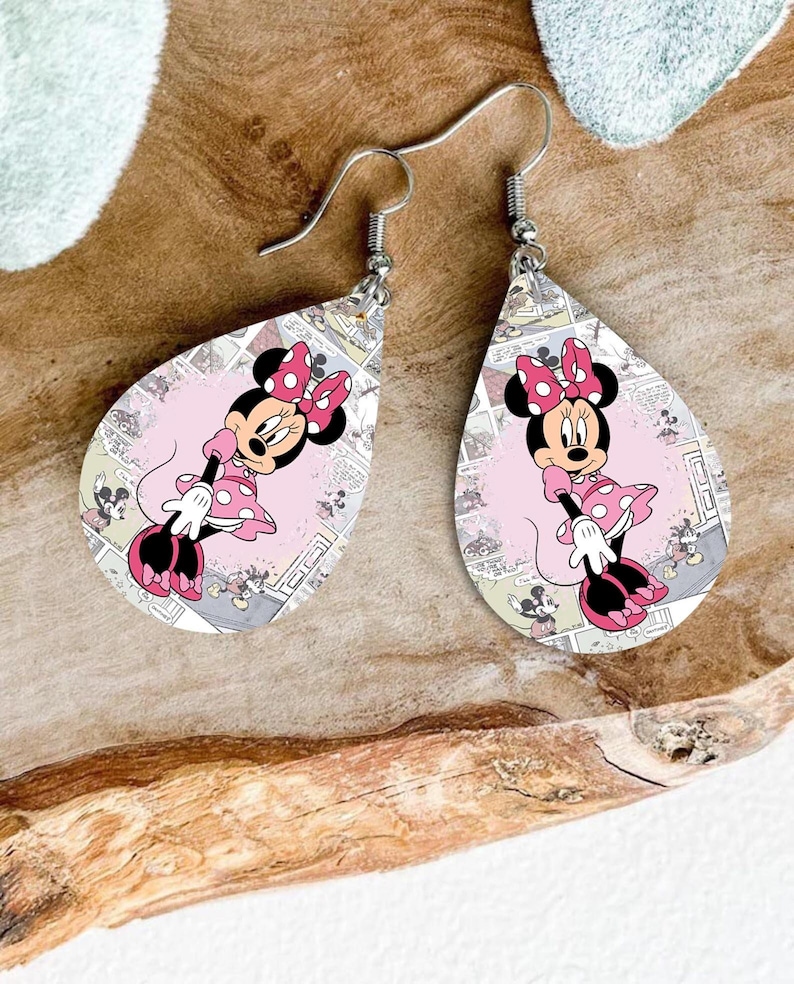 Op de afbeelding: Een paar druppelvormige oorbellen met Minnie Mouse. De oorbellen hebben een roze achtergrond met een stripontwerp en een Minnie Mouse-afbeelding. De oorbellen hebben zilverkleurige oorhaken.